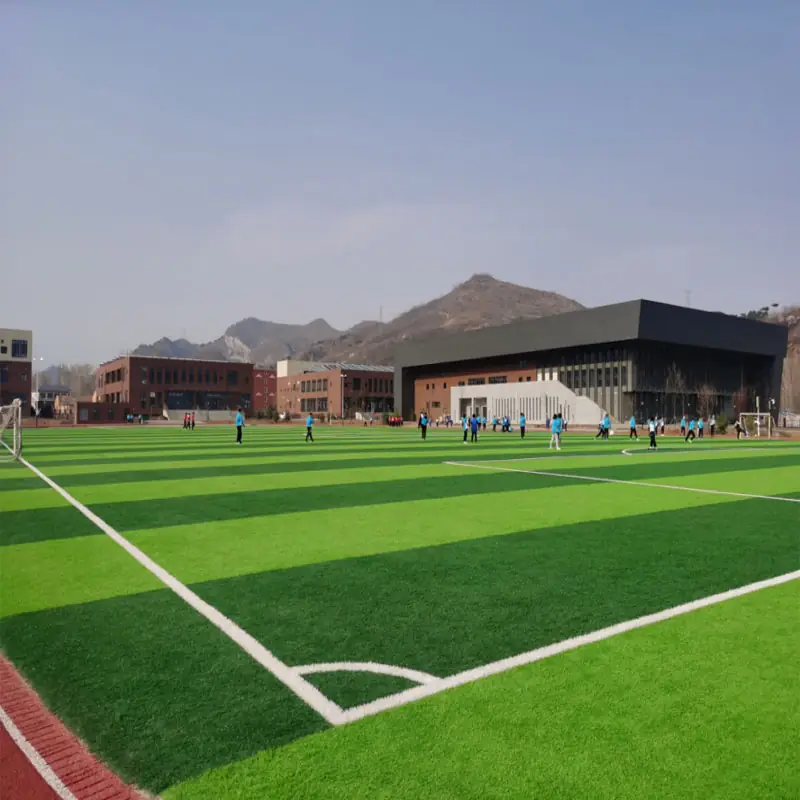 artificial football turf field with green striped grass, white markings, and players in an outdoor sports facility.(2)